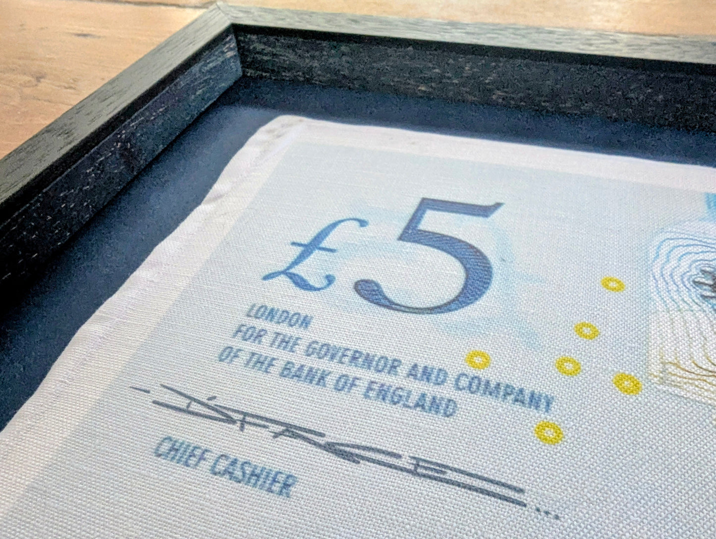 Close-up of a £5 banknote with text and design details.