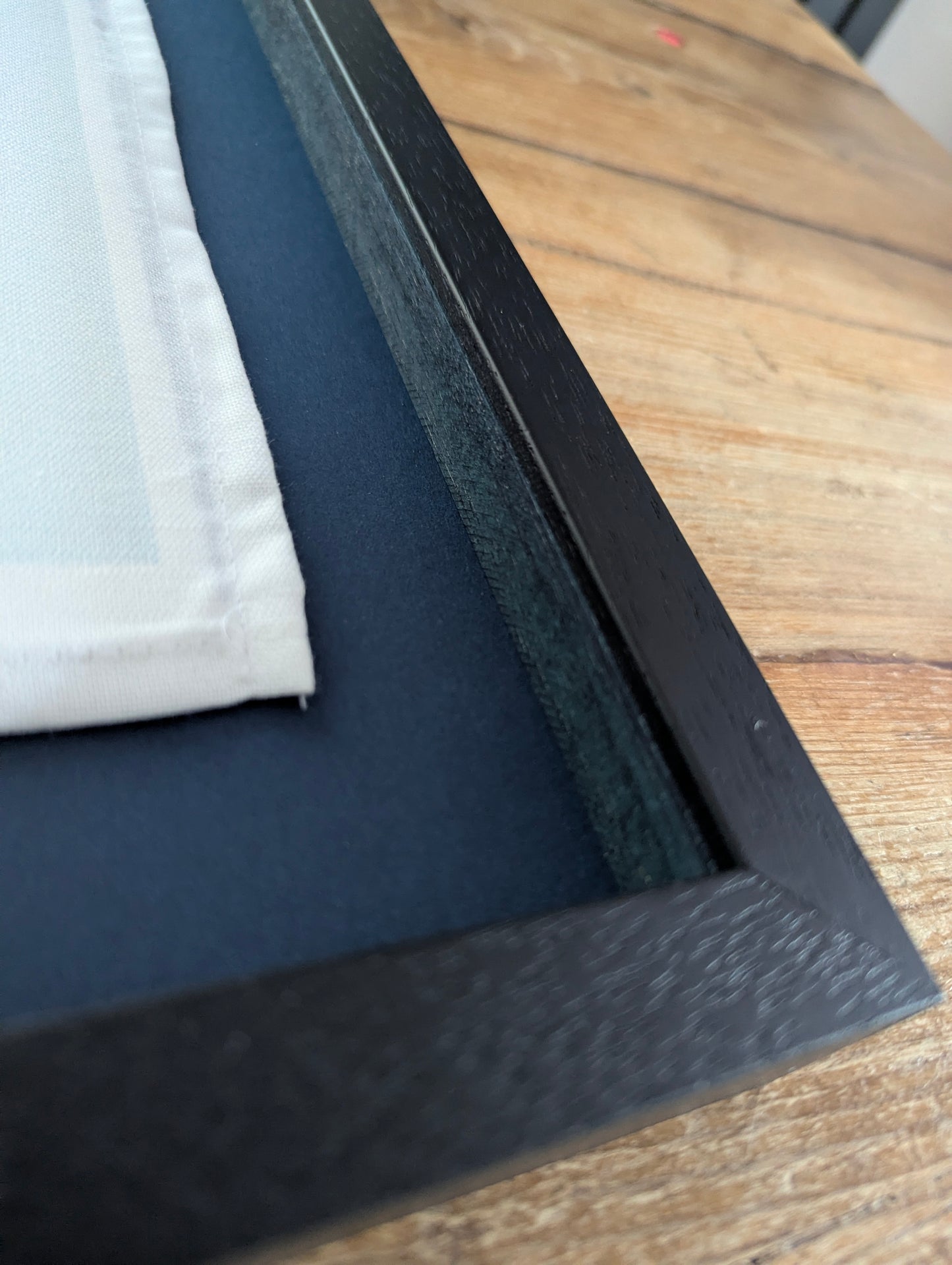 Close-up of a black frame corner on a wooden surface