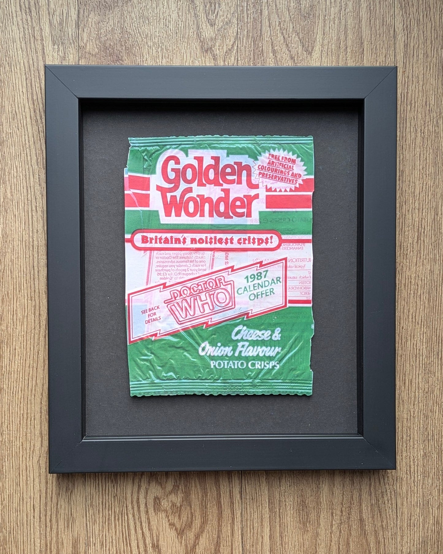 Framed Golden Wonder potato chips packet on a wooden surface