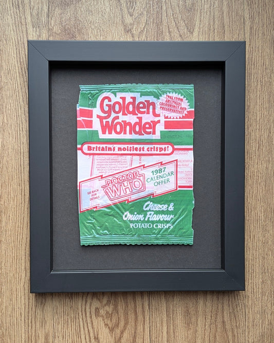 Framed Golden Wonder potato chips packet on a wooden surface