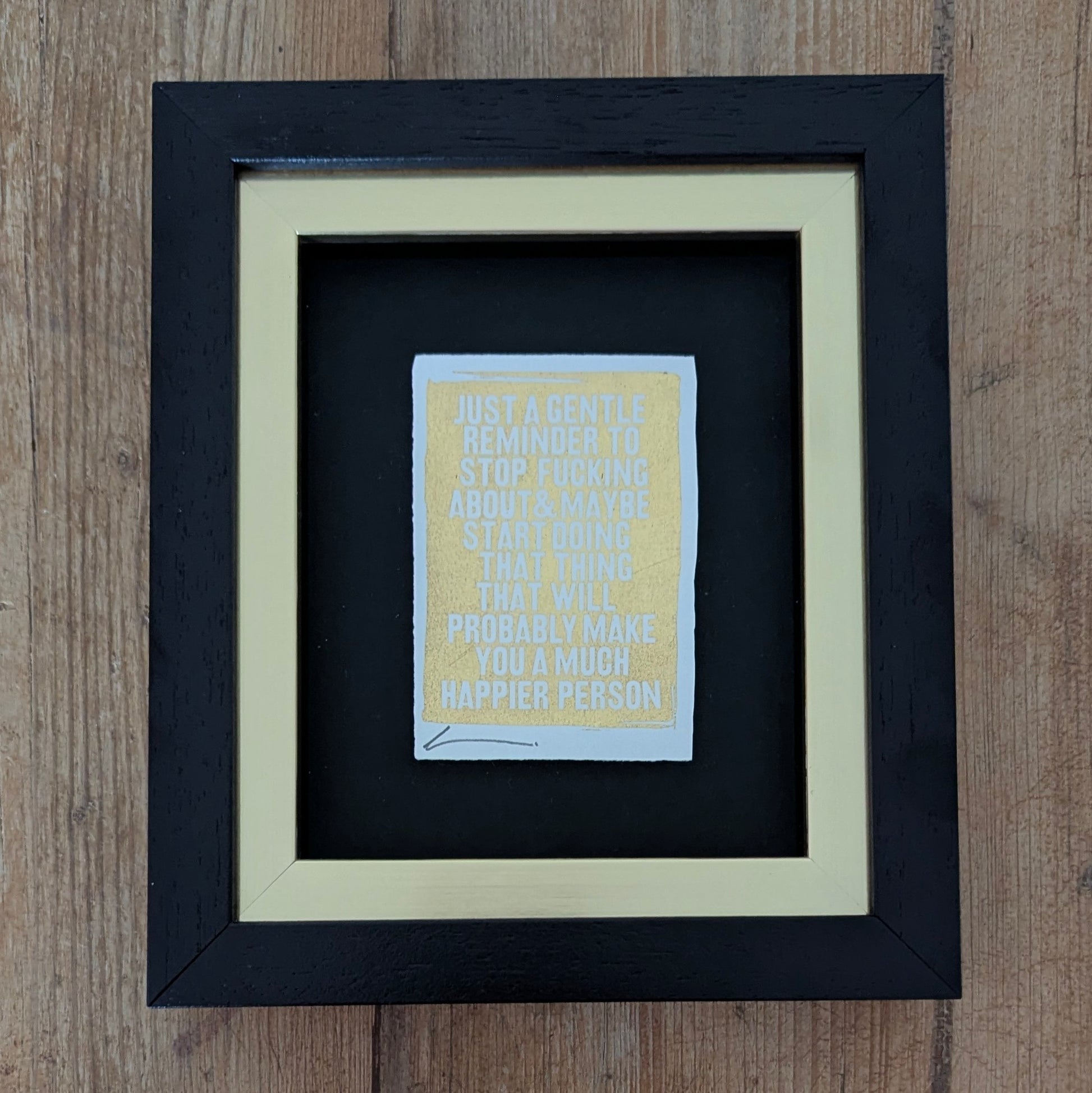 Framed Hackney Dave print with motivational quote printed with gold leaf on a wooden surface