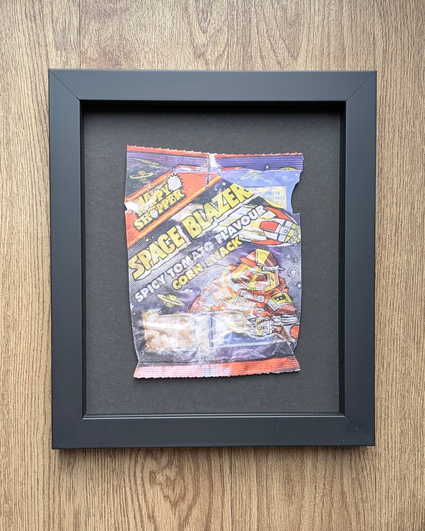 Framed vintage happy shopper crisp wrapper on a wooden surfaces