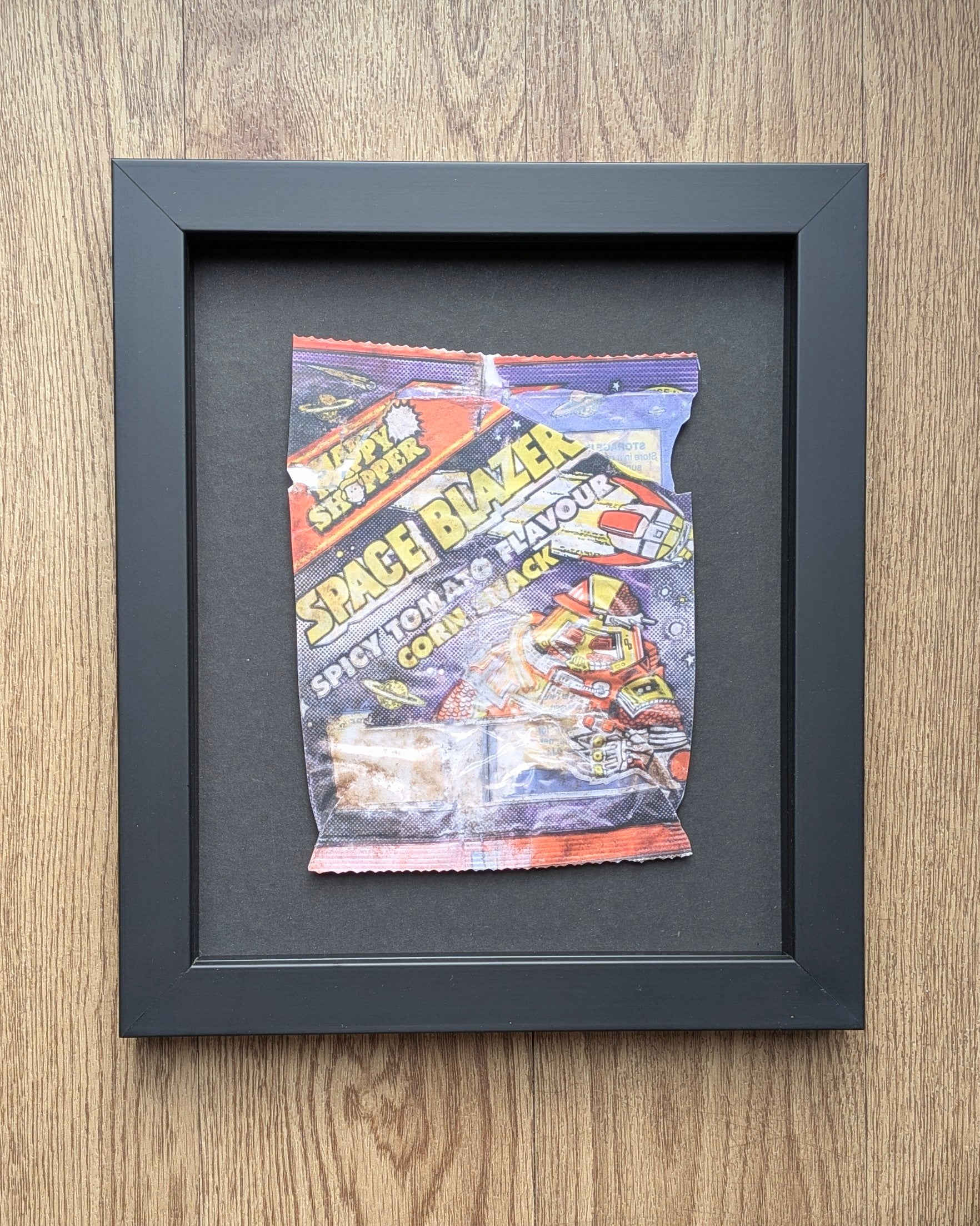 Framed vintage happy shopper crisp wrapper on a wooden surfaces