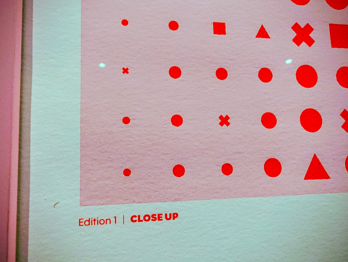 Close-up of a pink surface with red geometric shapes and text.