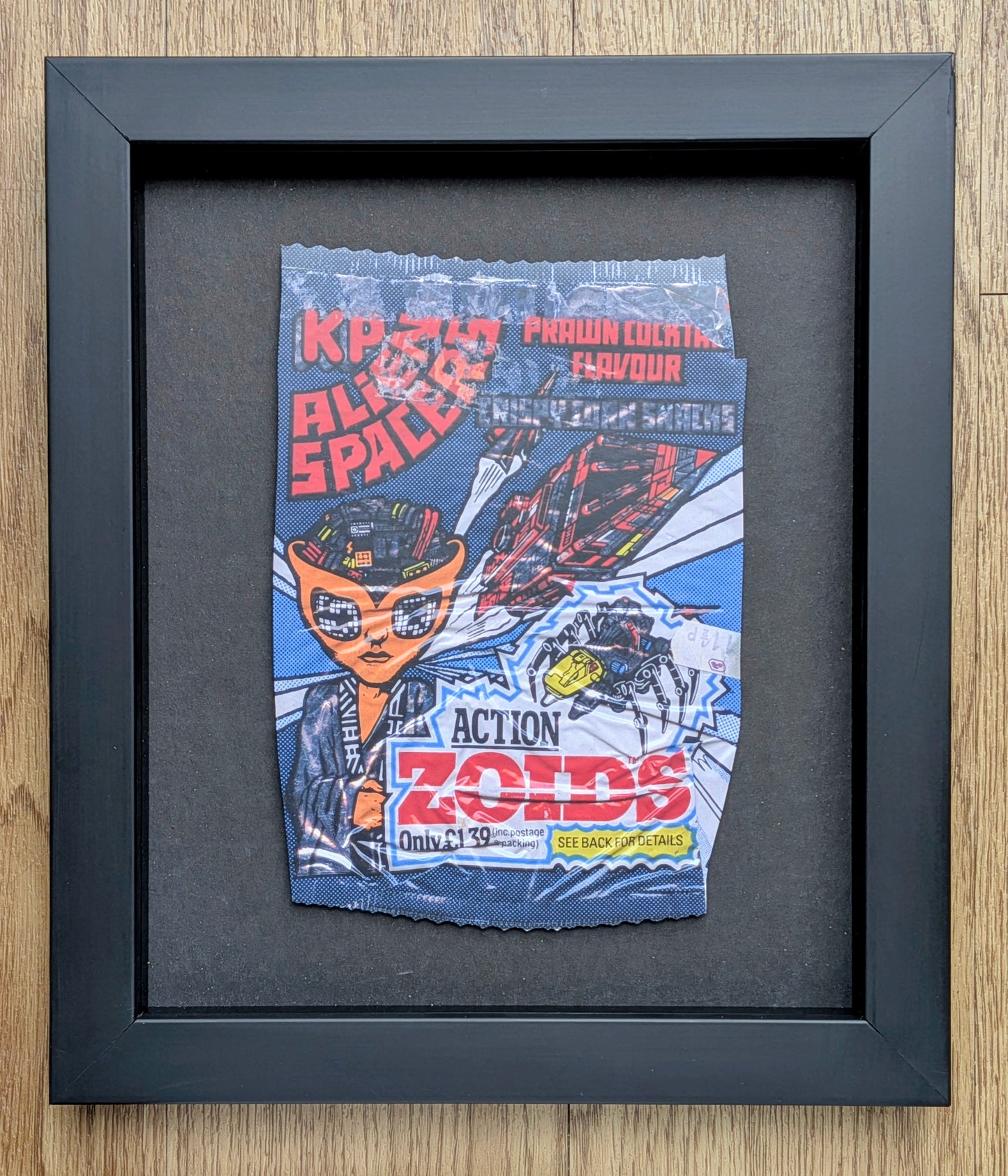 Framed vintage-style toy packaging with character illustration on a wooden surface