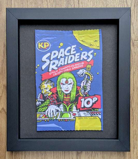 Framed illustration of a retro-style snack packet labeled 'Space Raiders' on a wooden surface.