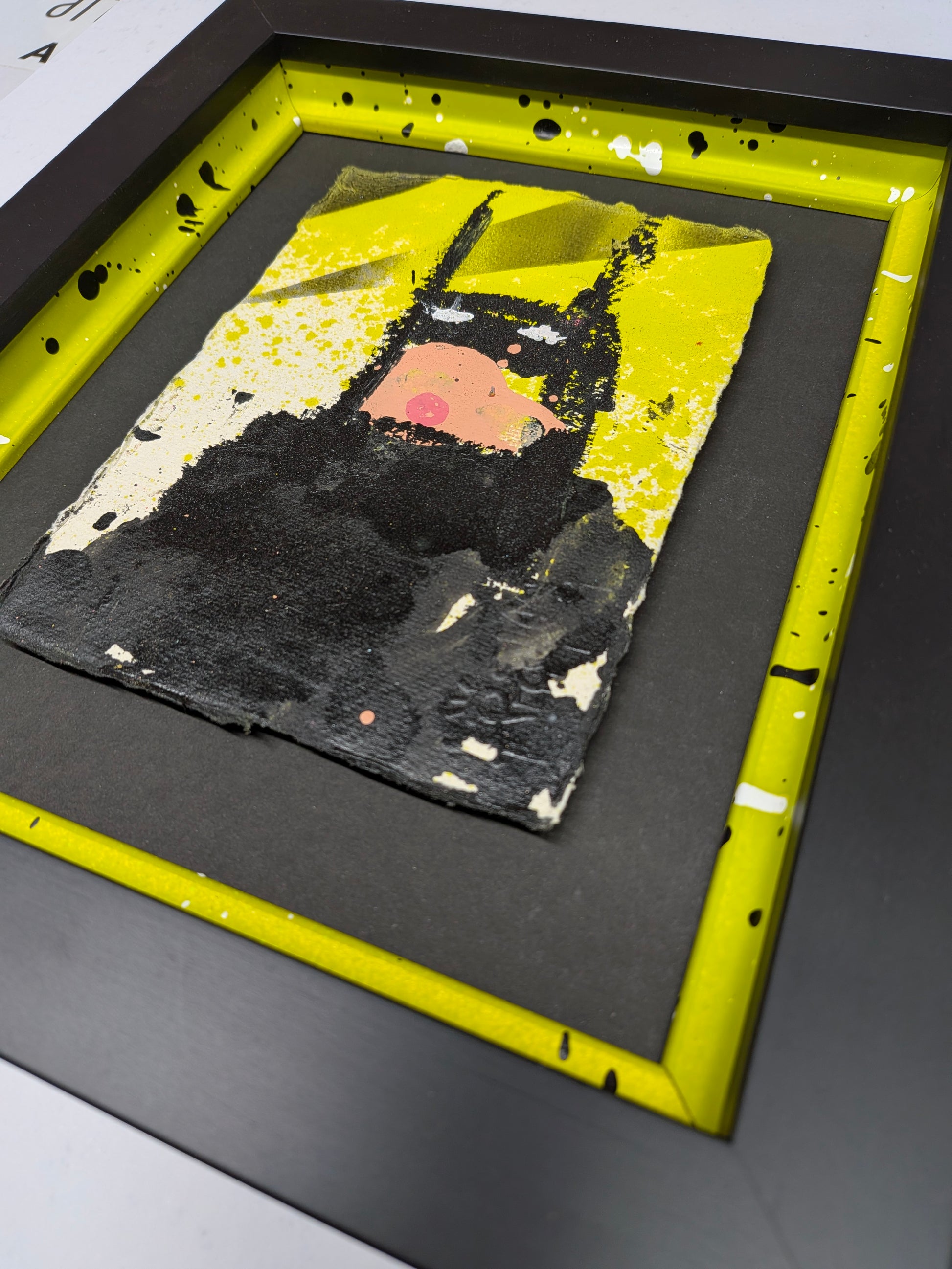 Framed artwork with a black batman figure on a yellow background