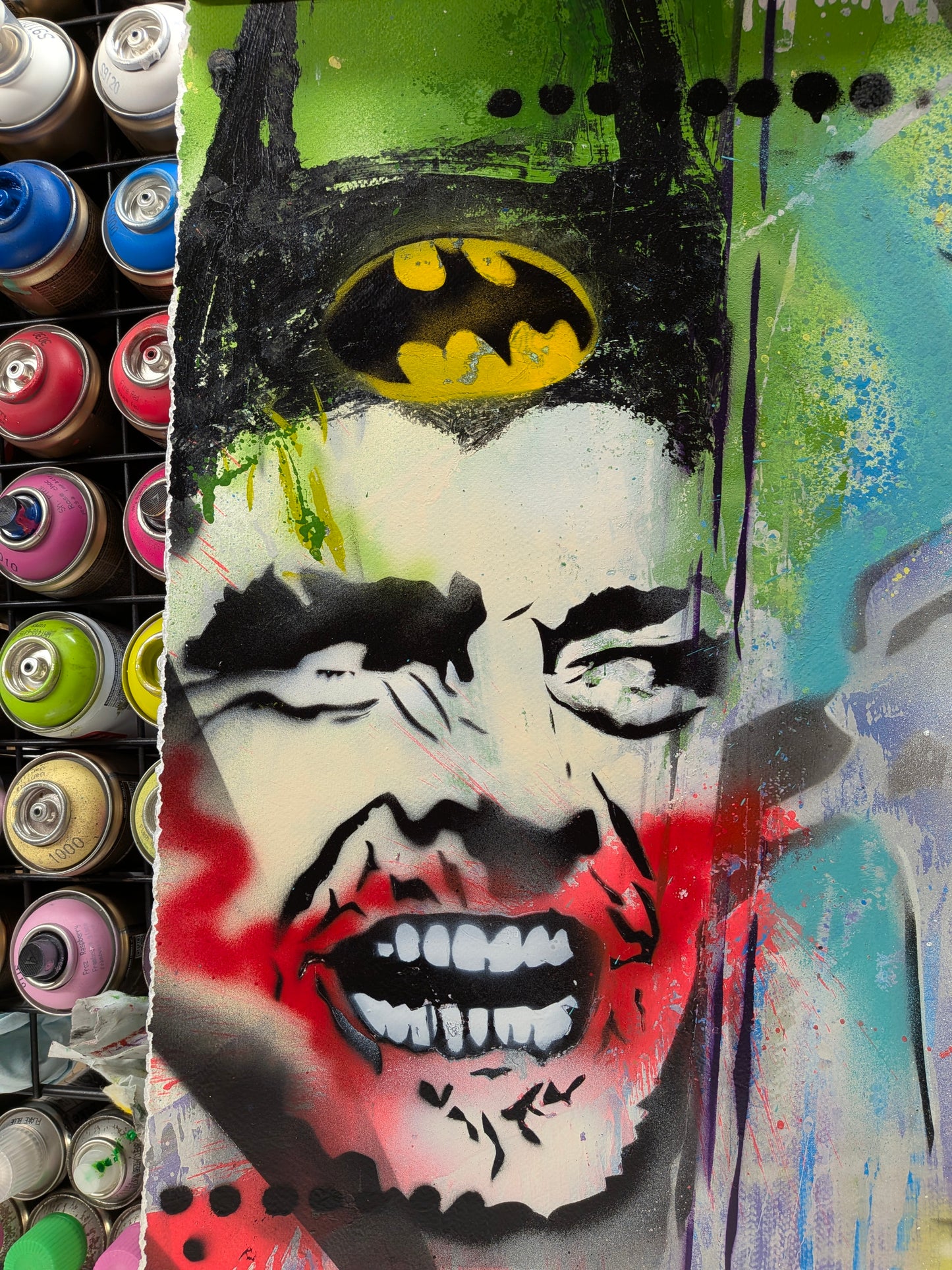 Graffiti-style artwork of a face with a Batman logo on a colorful background.
