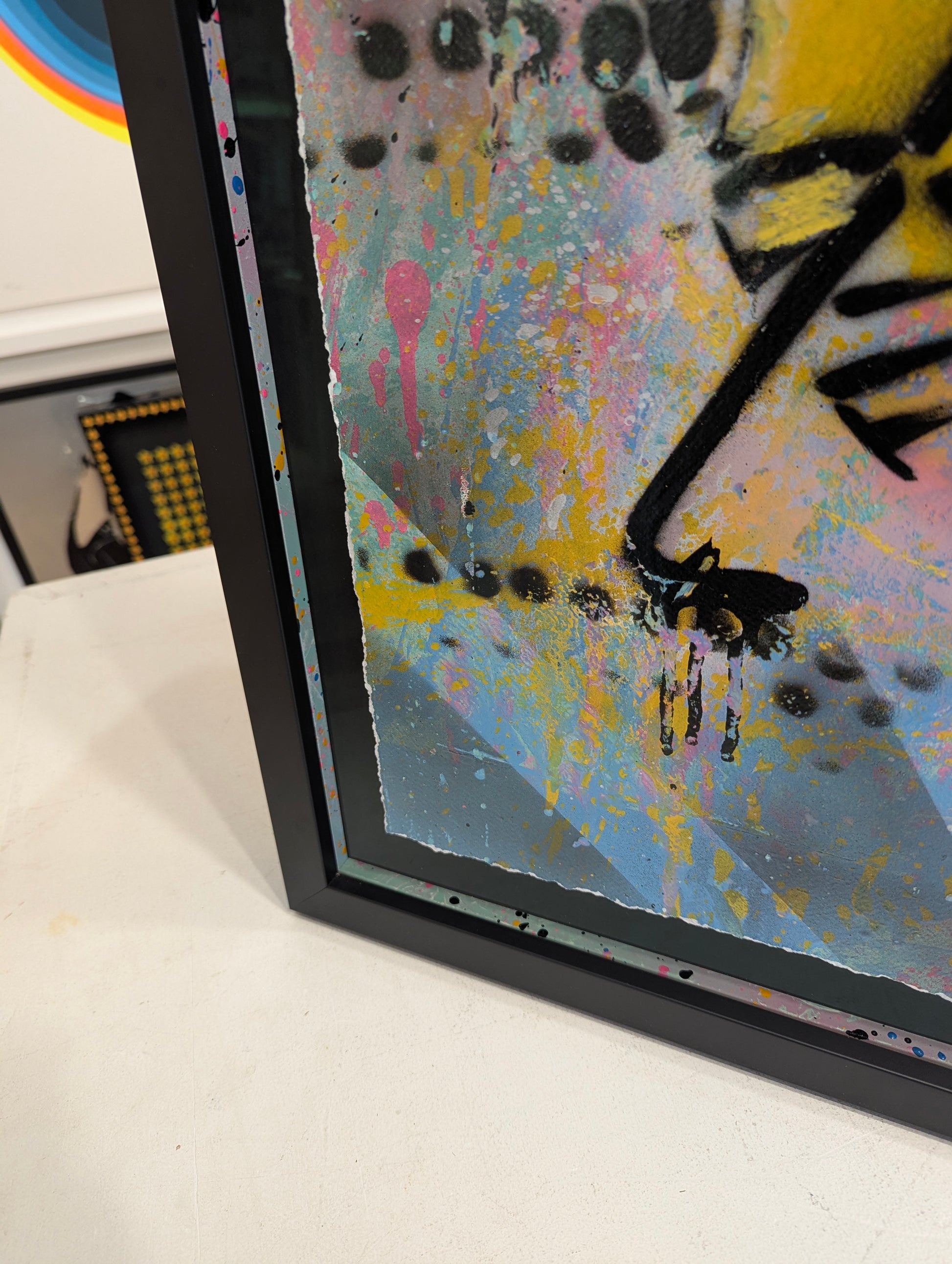 Colorful abstract painting with a black frame on a white surface