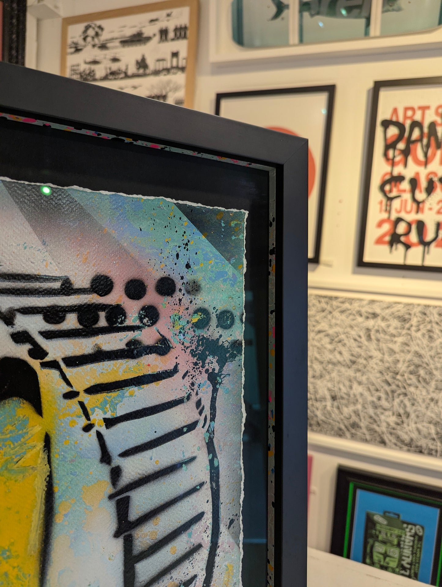 Framed abstract artwork with colorful design on a wall with other framed items.