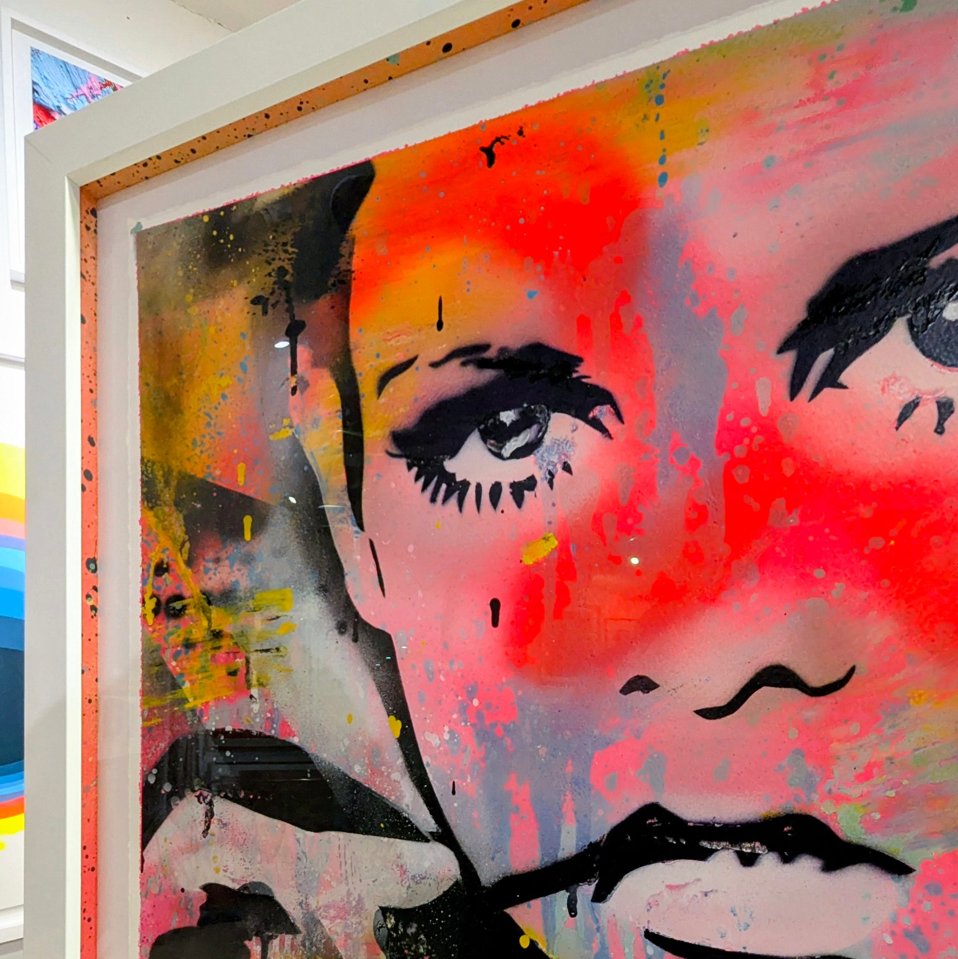 abstract bright colours of twiggys face framed in white frame in an gallery, top right corner of frame