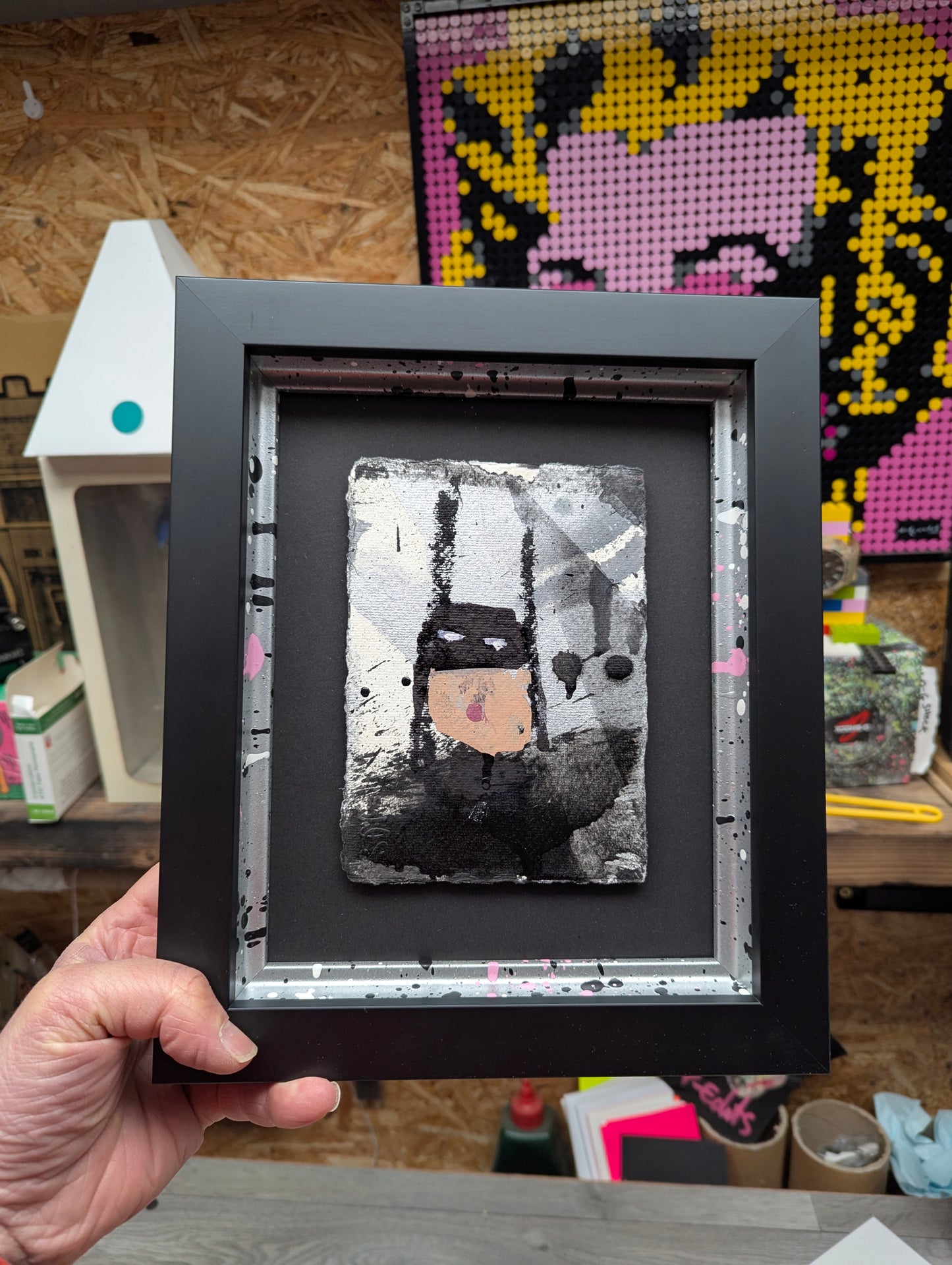 cartoon batman in black and silver frame, artwork in background