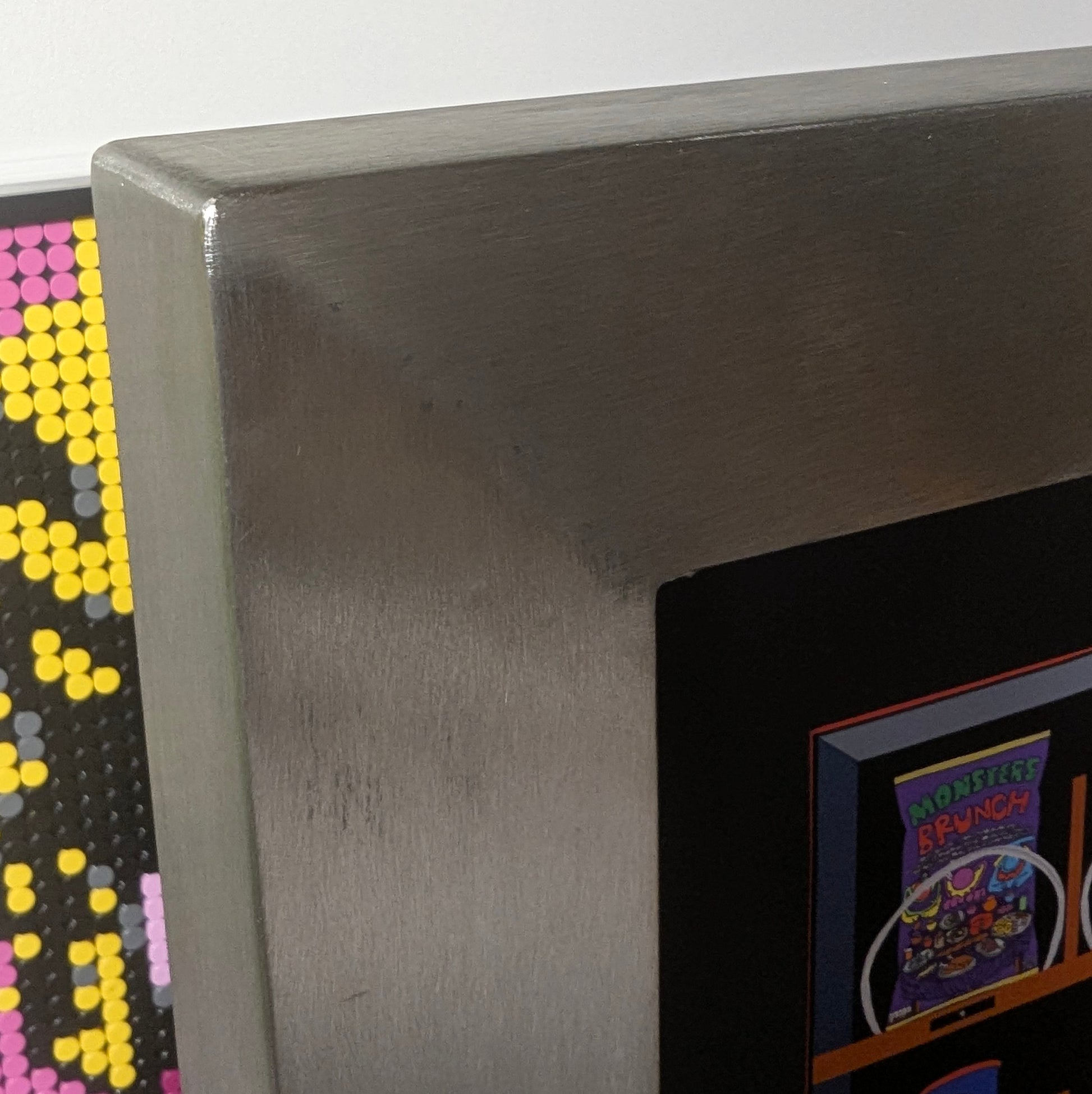Close-up of a stainless steel welded frame for artwork against a dark background