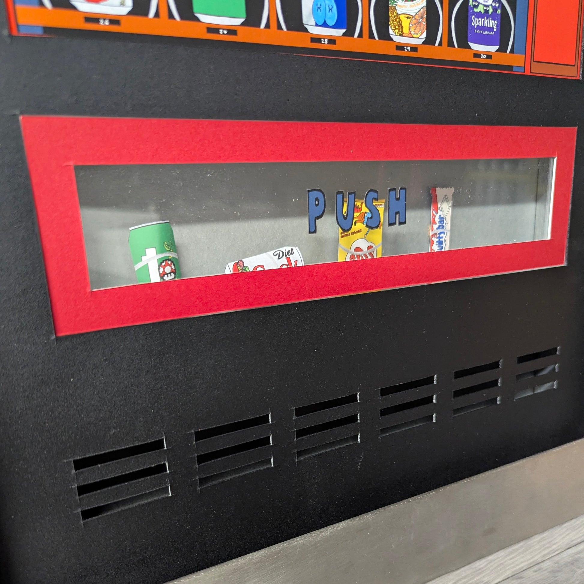 Black vending machine with a red push panel displaying various items.