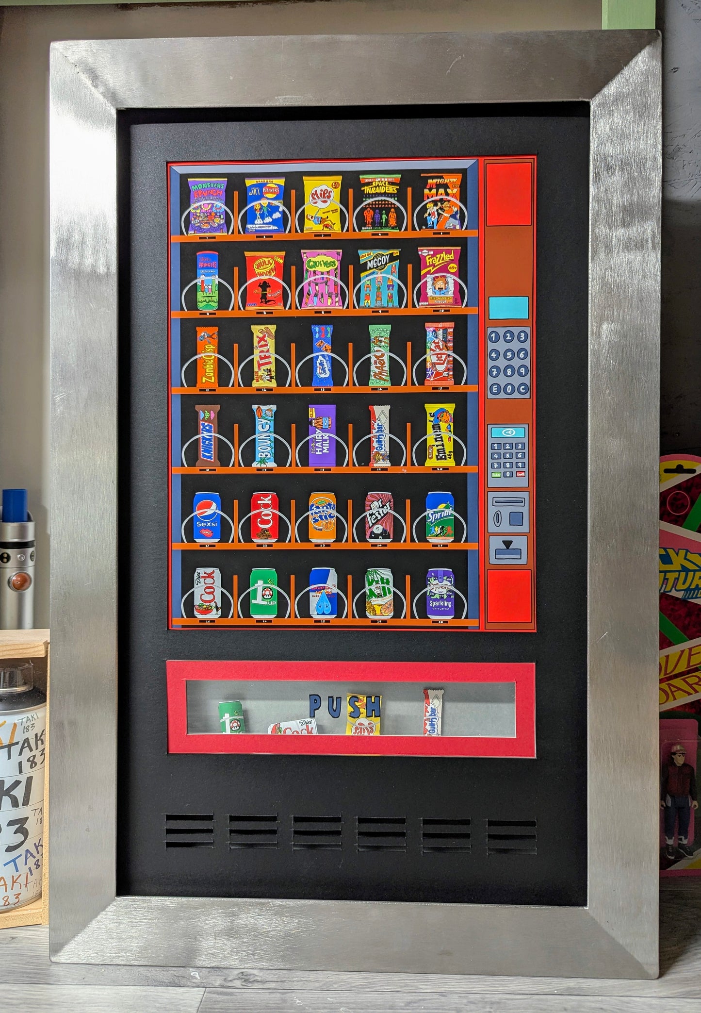 art work shows a cartoon vending machine by multi ego, it has been custom framed in a welded stainless steel frame.