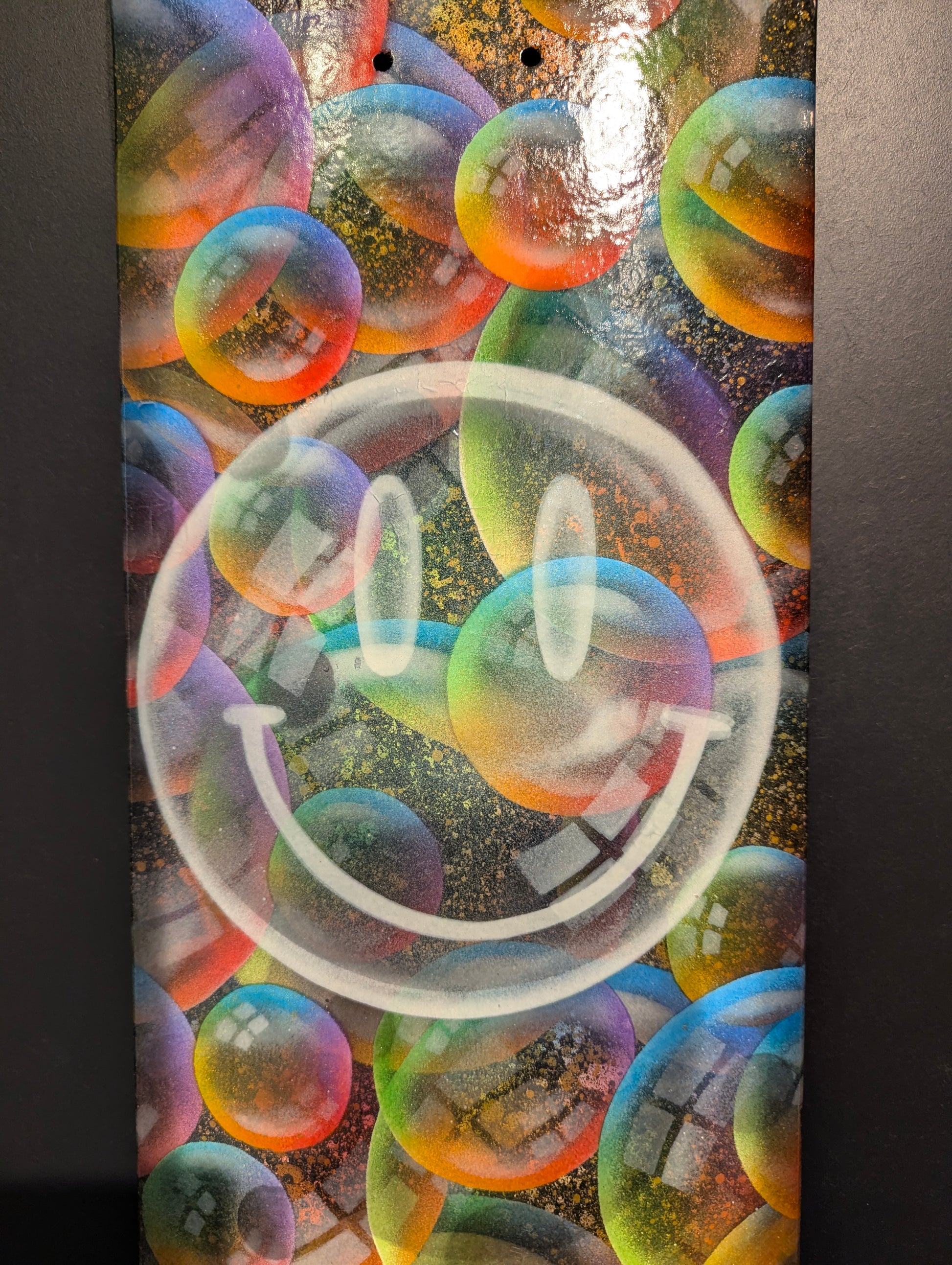 Colourful bubble wrap with a smiley face design on a dark background