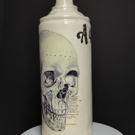 video of ceramic spray rotating on base, can is by Adam Graddon, spraycan is cream ceramic with blue skull