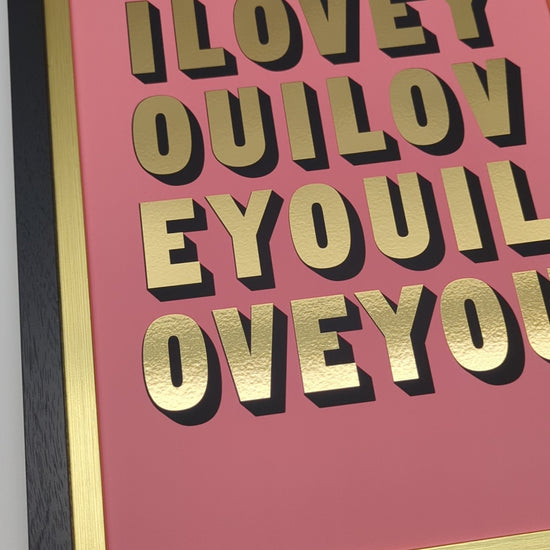 short video of framed artwork with 'ILOVEYOU' in gold text on a pink background, displayed on a wall