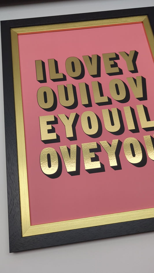 short video of framed artwork with 'ILOVEYOU' in gold text on a pink background, displayed on a wall