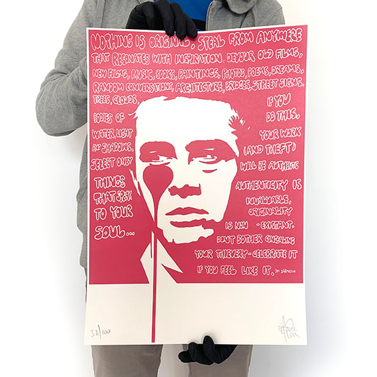 A person holding a limited edition  Pure Evil James Dean print featuring a stylized, red-colored portrait with text.