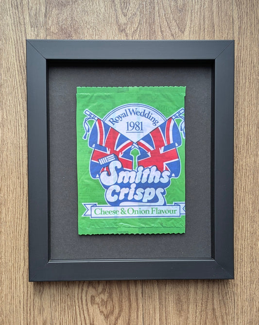 Framed Smiths Crisps packet with Union Jack design on a wooden surface