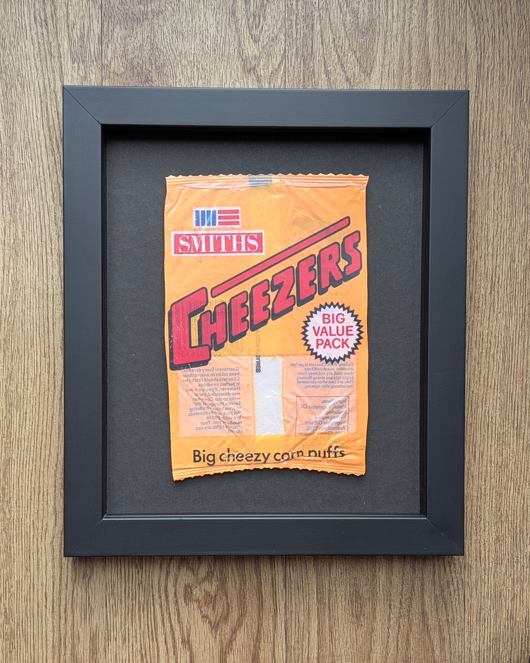 Framed Smiths Cheezeers snack packet on a wooden surface
