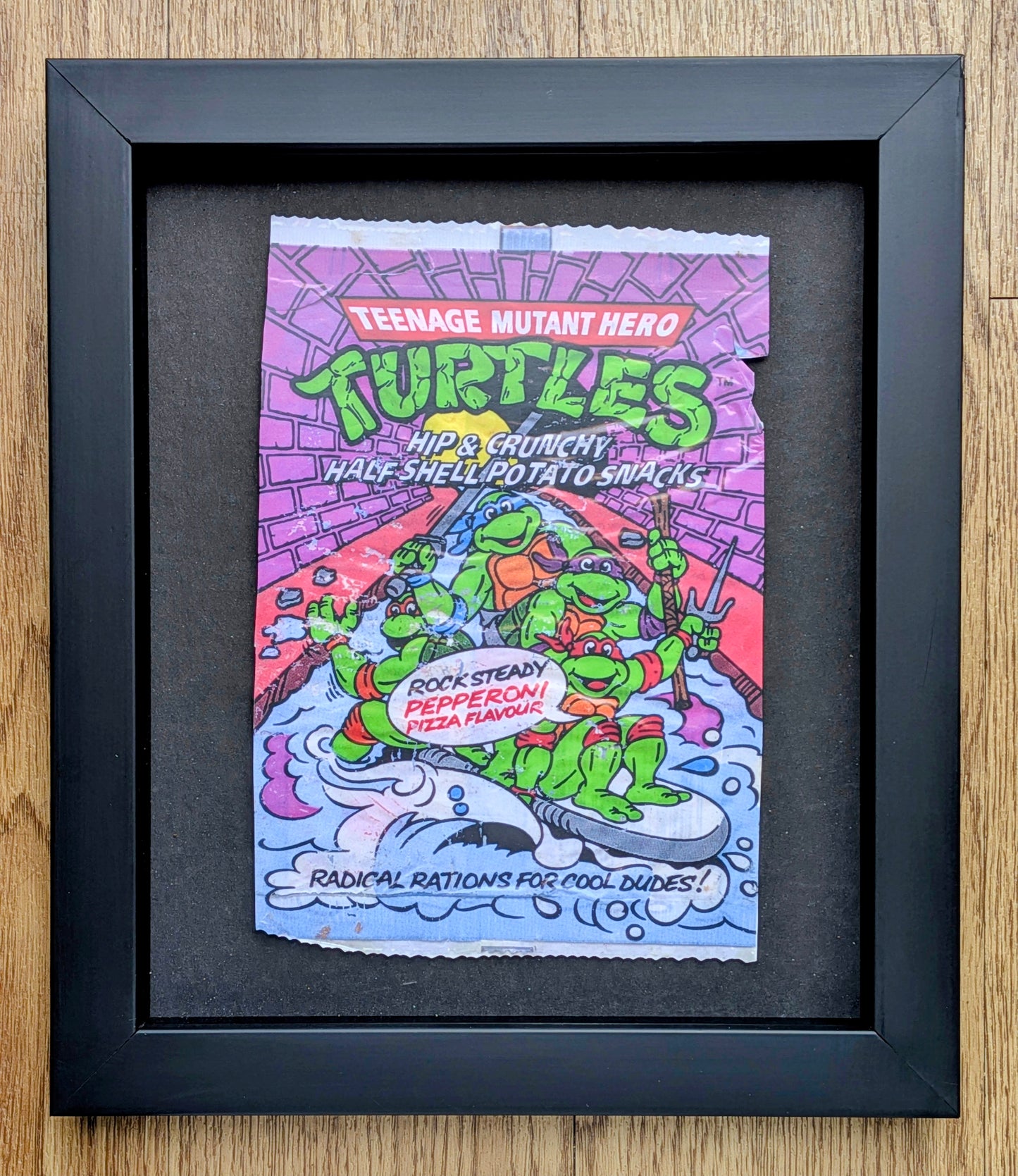 Framed poster of Teenage Mutant Hero Turtles packaging on a wooden surface