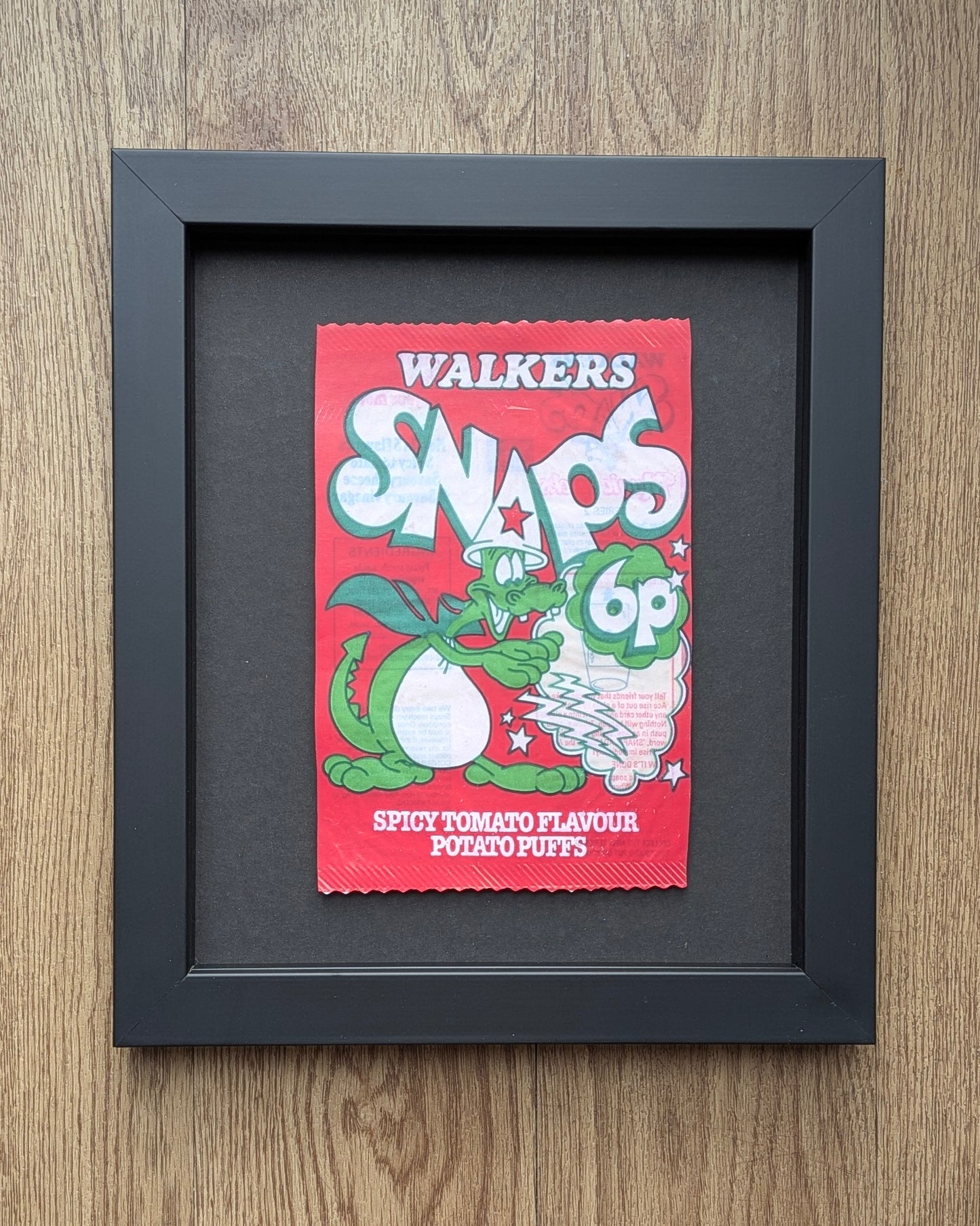 Framed Walkers Snaps spicy tomato flavour packet on a wooden surface