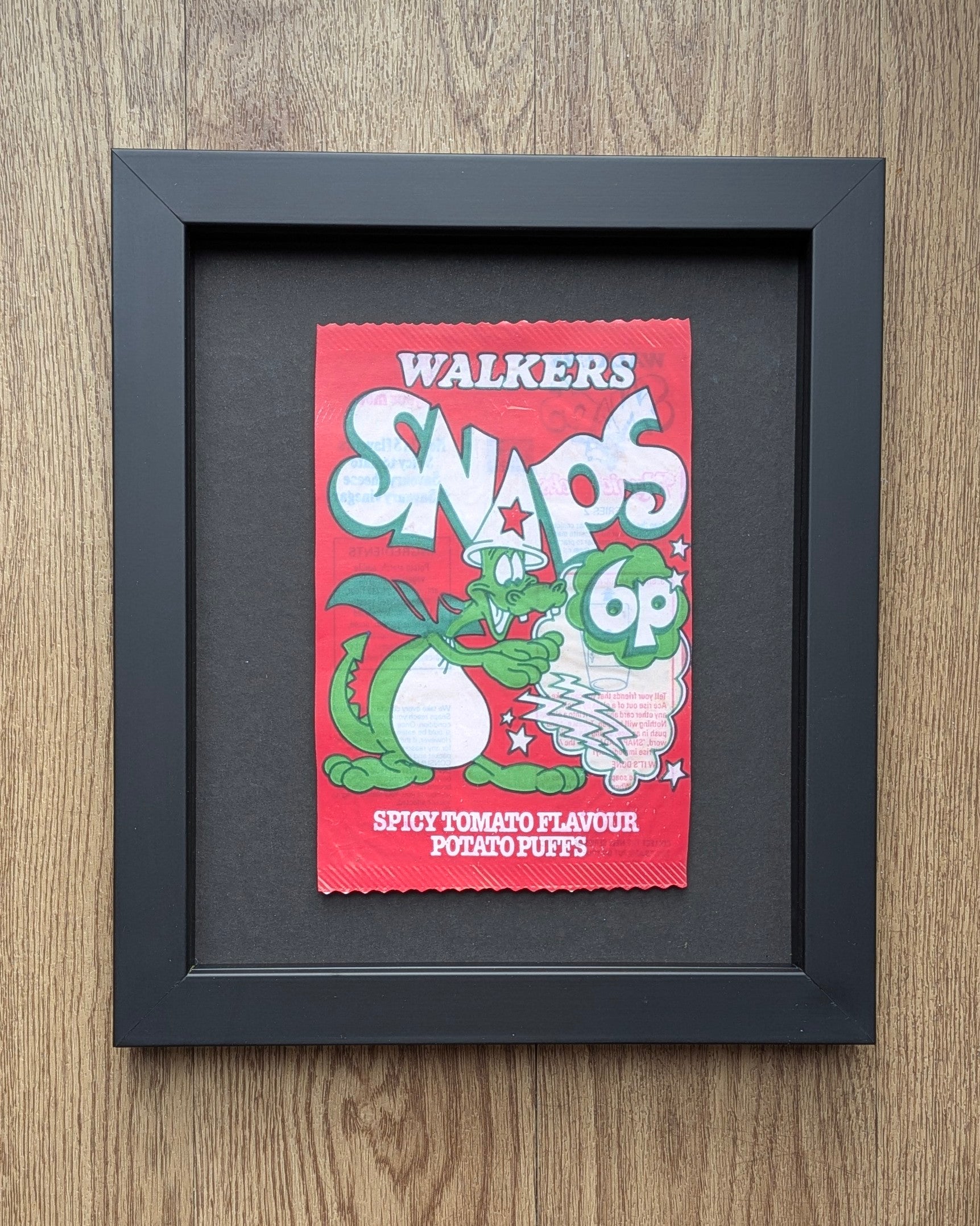 Framed Walkers Snaps spicy tomato flavour packet on a wooden surface