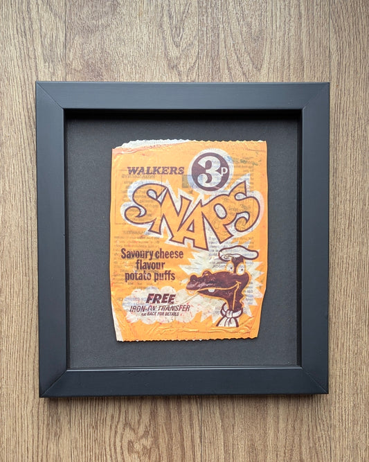 Framed picture of a vintage Walkers Snaps packet on a wooden surface