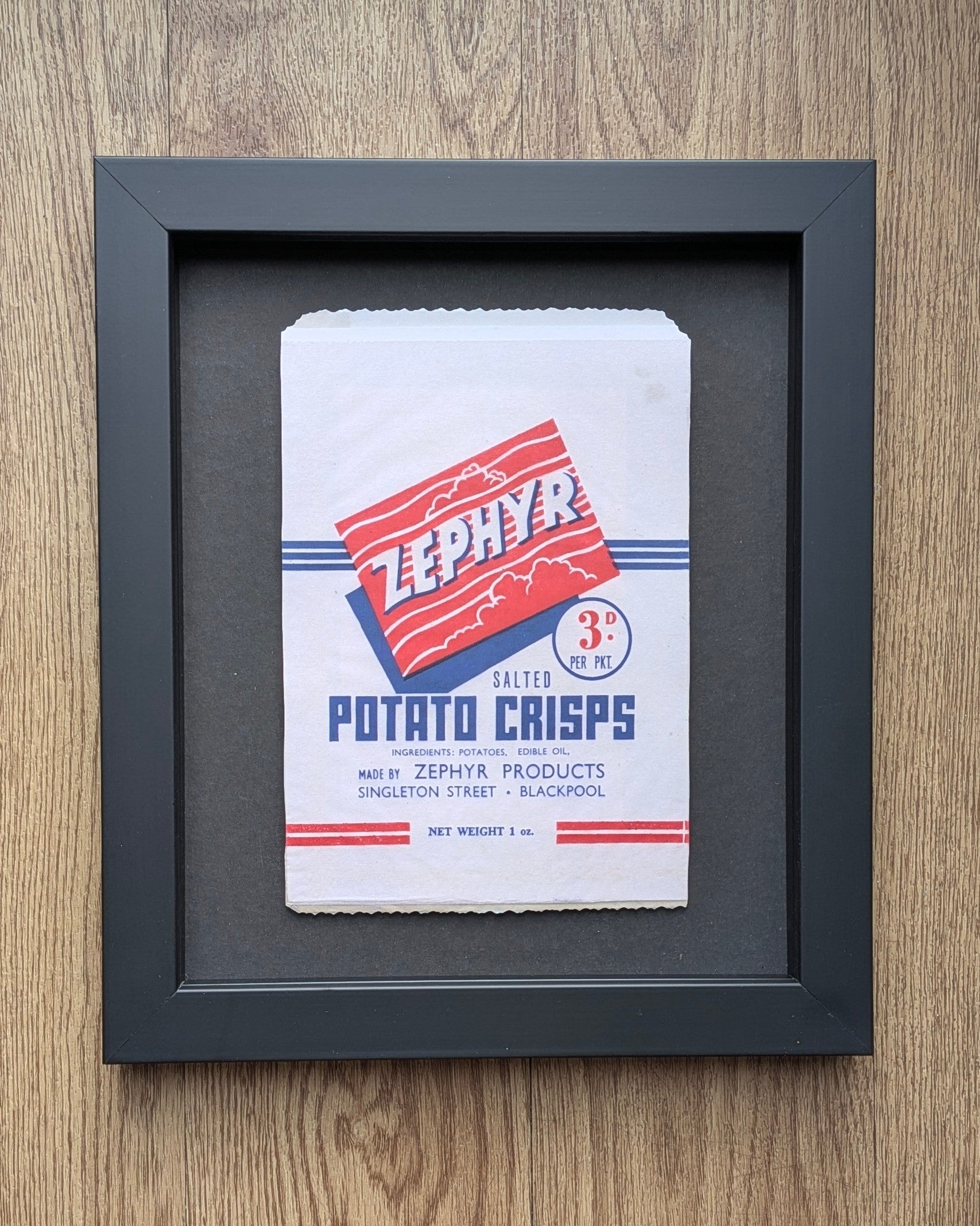Framed Zephyr Potato Crisps packaging on a wooden surface